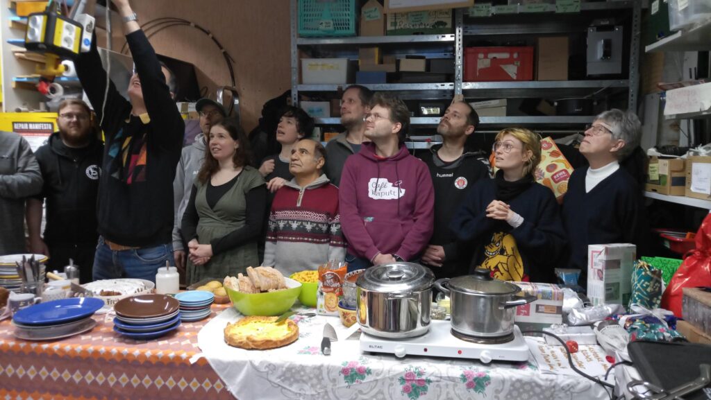 Mehrere Menschen sthen hinter einem gedeckten Buffet und blicken alle in die falsche Richtung, n&auml;mlich zu einer Person links um Bild, anstatt in die Kamera.