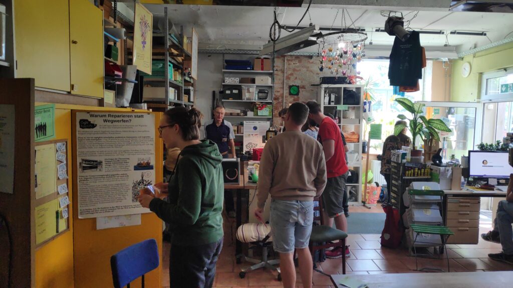 Mehrere Menschen stehen in Caf&eacute; kaputt und erkunden den Raum.