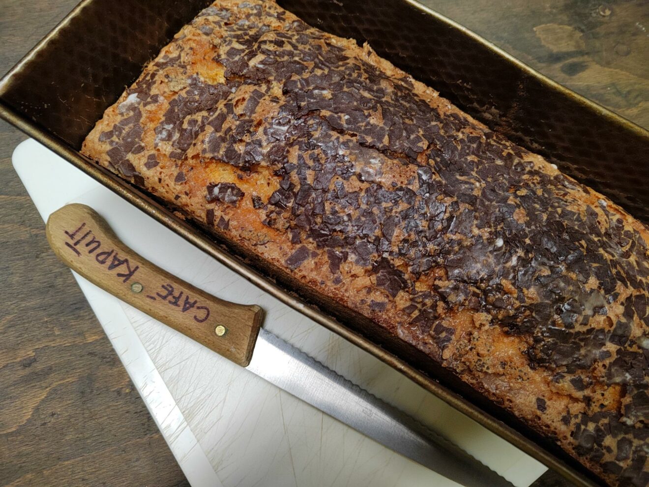 Auf dem Bild ist der Eierlikörkuchen in einer länglichen Backform zu sehen. Daneben liegt ein Messer worauf Café kaputt geschrieben ist.