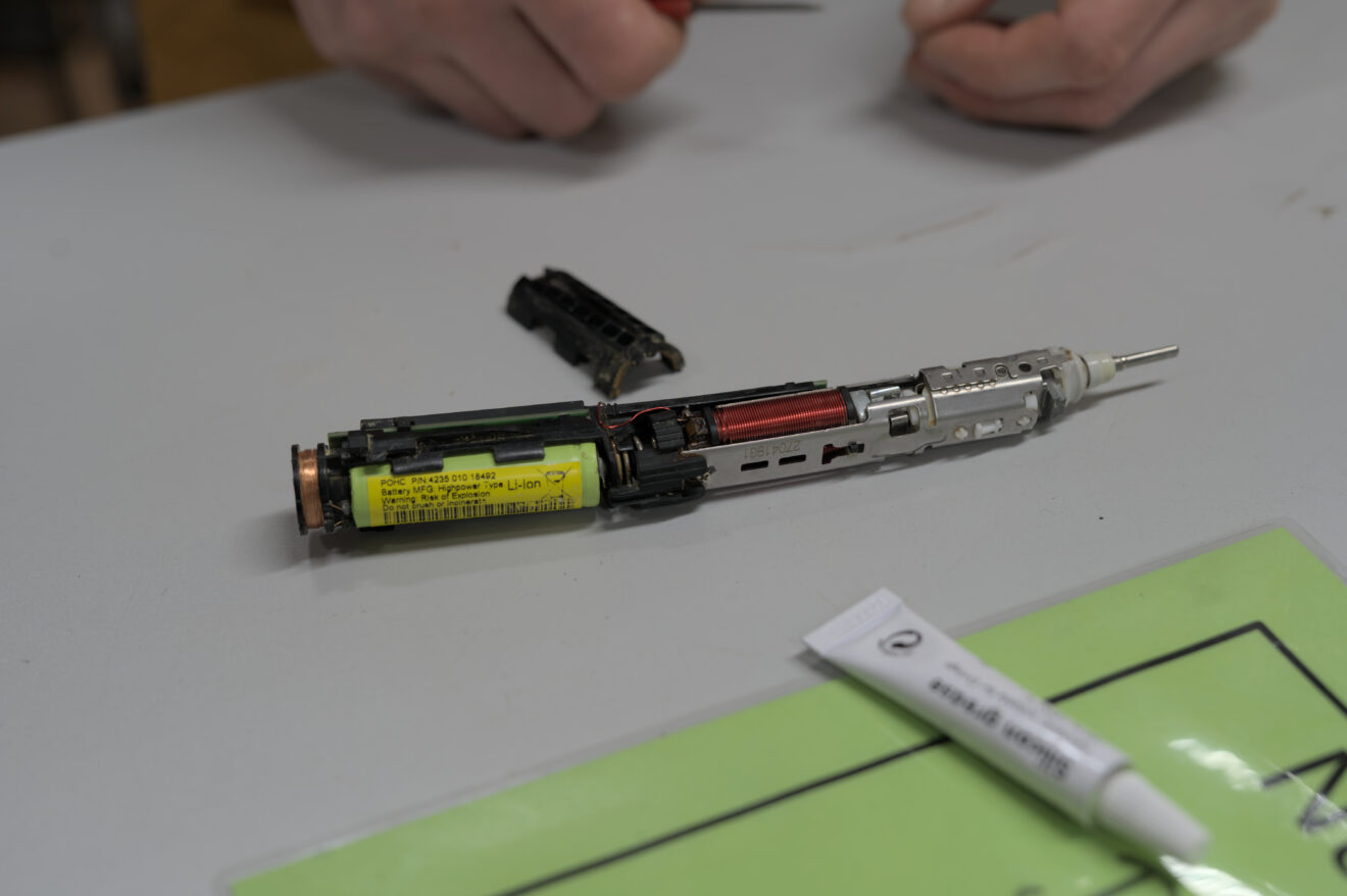 Das Innenleben einer elektrischen Zahnbürste liegt auf einem weßen Tisch.