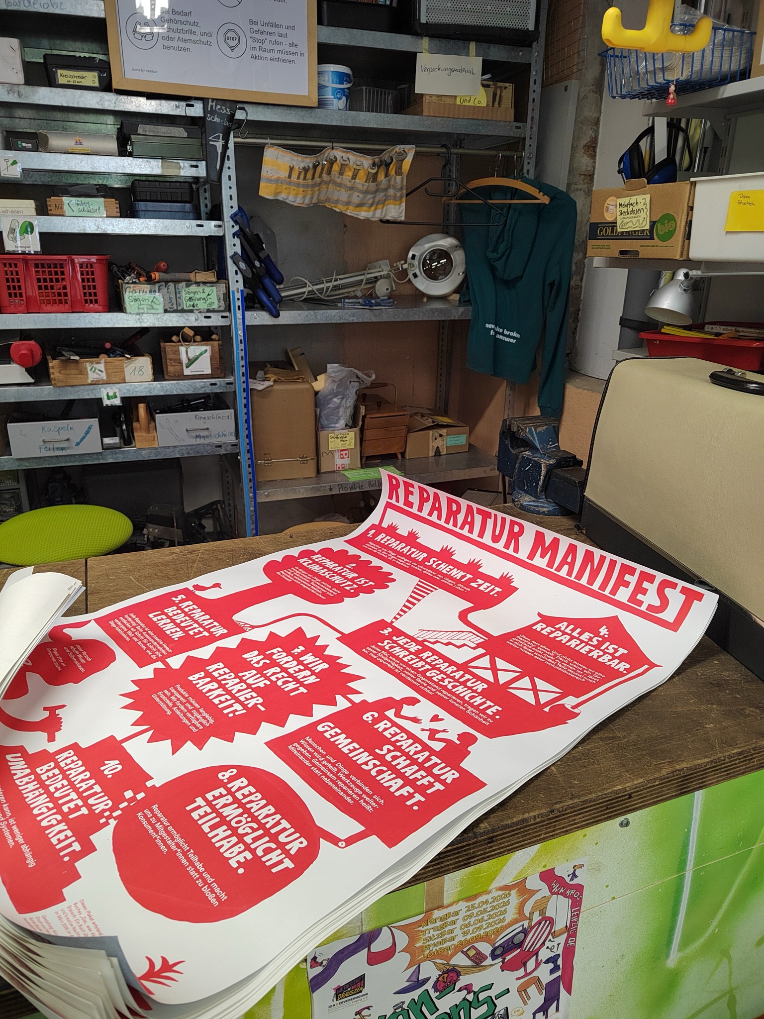 Poster "Reparatur-Manifest" in Rot. Sie liegen auf einem Tisch.